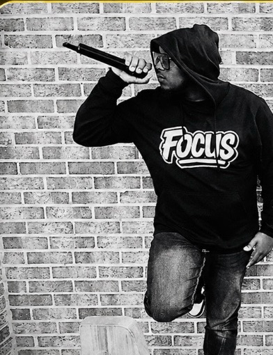 Focus single artwork: Sheldon Brown in a Focus hoodie against a brick wall